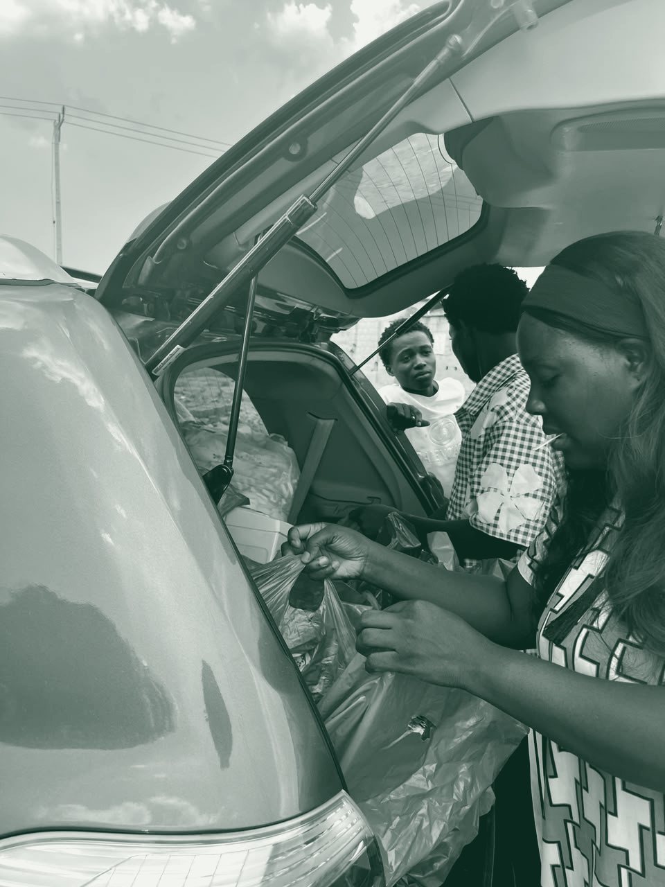 A volunteer hands a bag of supplies to a family beside a vehicle.