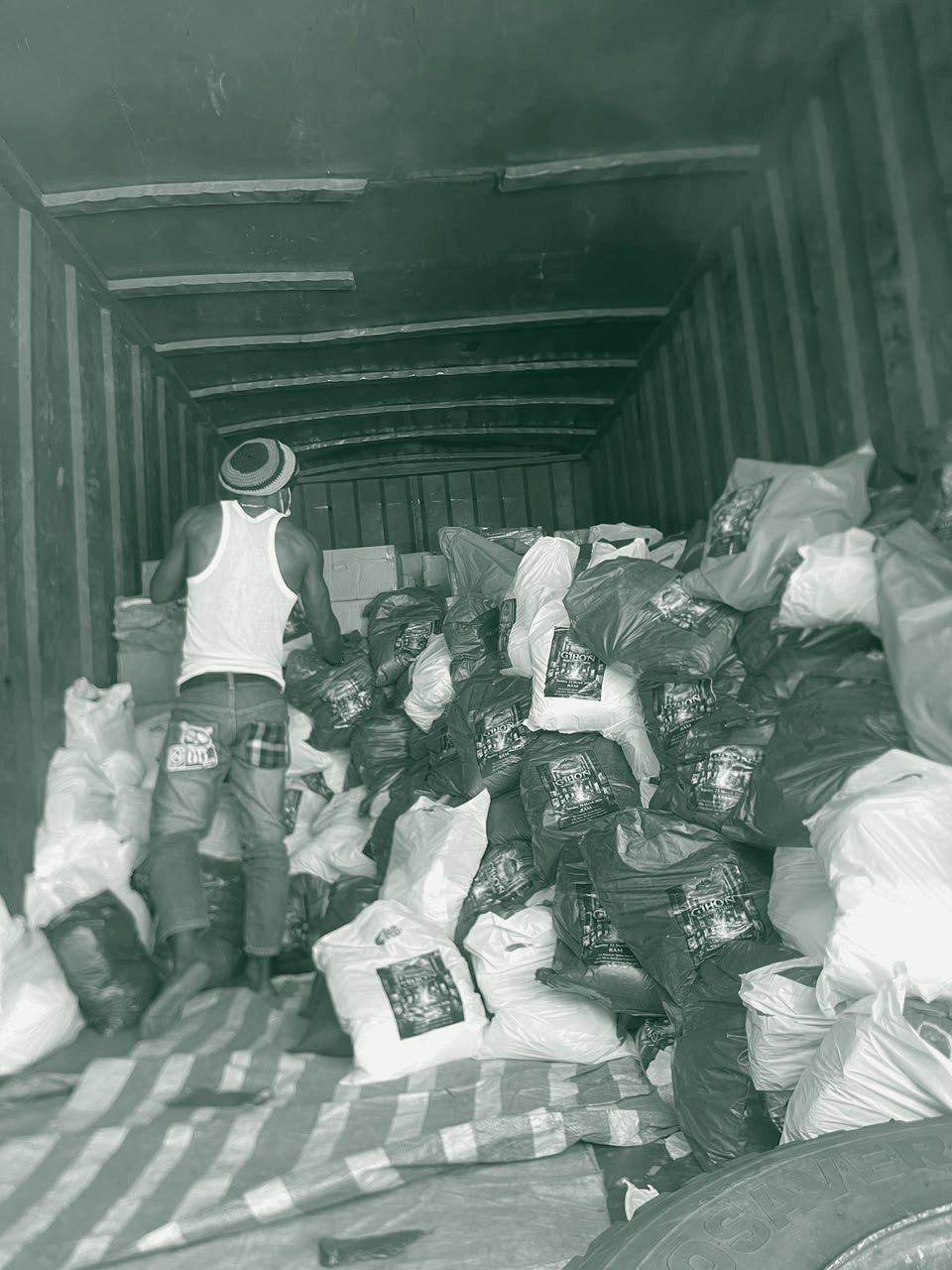 A volunteer stands among a truckload of food packages ready for distribution.